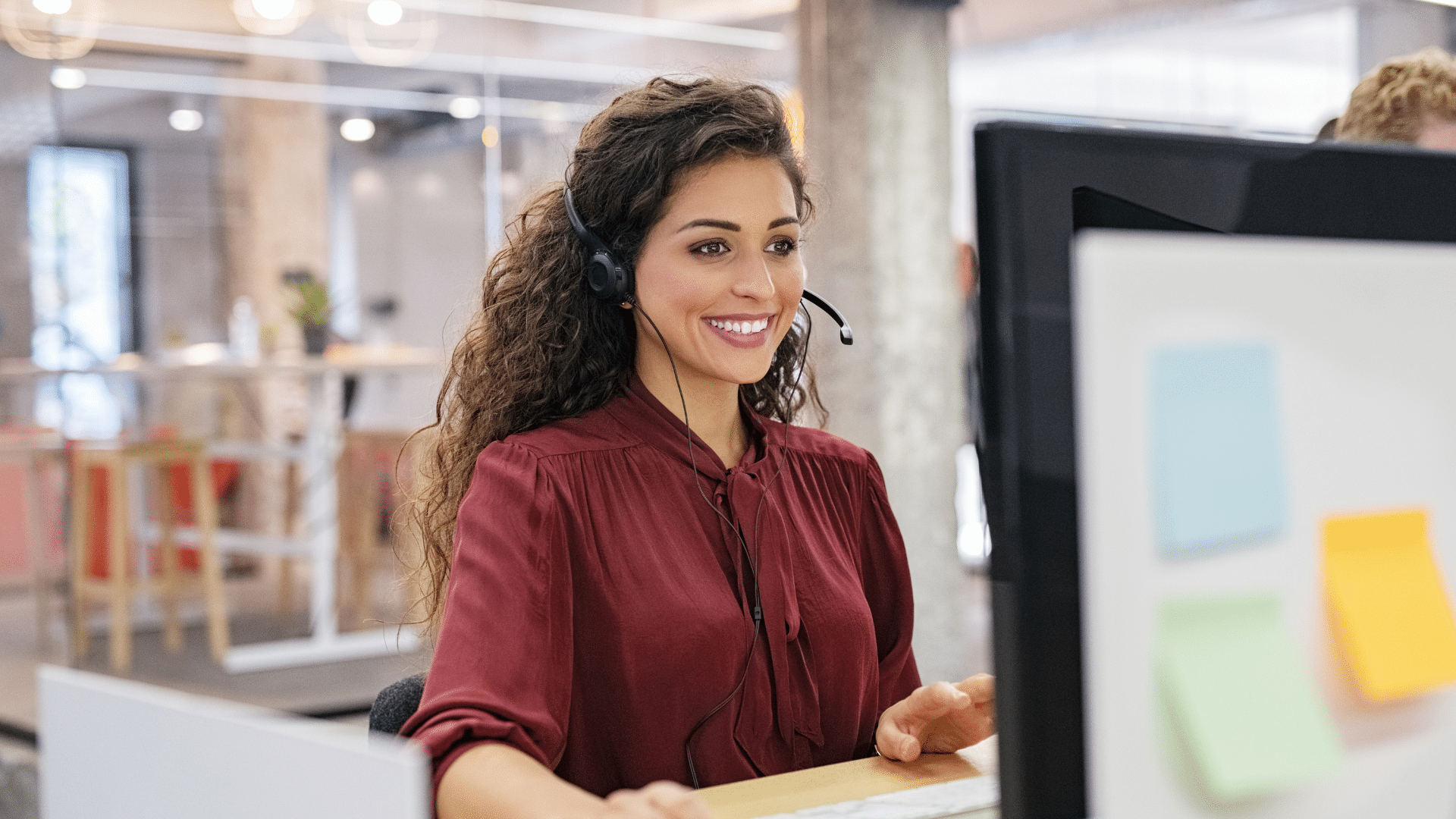 femme aux cheveux bouclés devant un écran d'ordinateur avec un casque